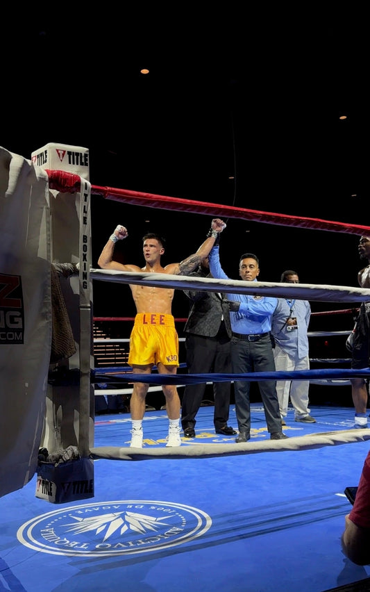 Hunter Lee raises his arms after a unanimous decision to move to 4–0 at Hard Rock Casino in Rockford, Illinois, wearing gold KRONK trunks.